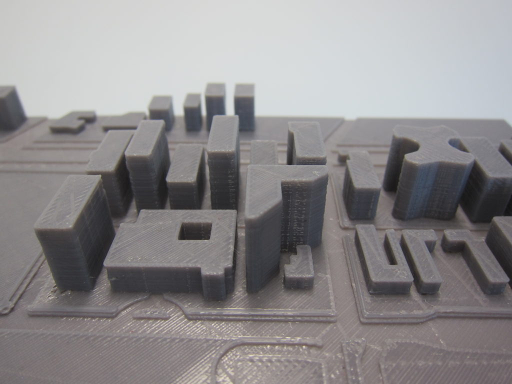 3D printed map with indented roads and buildings of varying shapes and heights. 