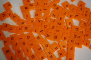 3D printed braille scrabble tiles with raised braille and indented print letters