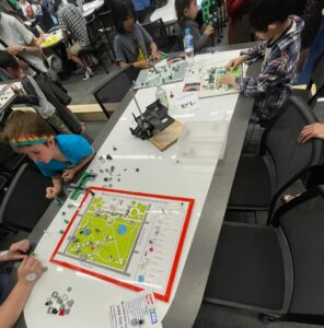 3D printed maps and map icons on a table surrounded by families and visitors