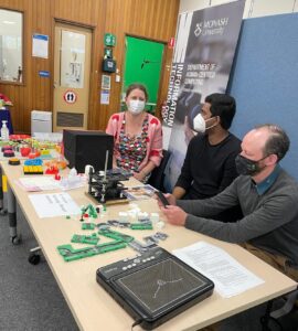 Leona, Bhanuka and Matt seated at a table with Tape Blocks, 3D prints and a refreshable tactile display