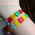 multi-colour letter beads on bracelets with braille on one side and indented black lettering on the other