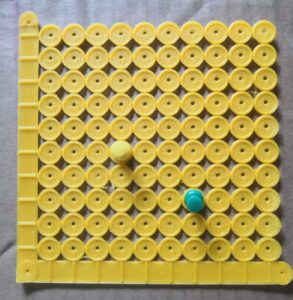 3D printed grid with flat axes, raised line markers on the axes, and one circle (with raised edges) per plot point. Push pins are inserted into two points. 