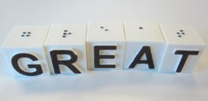 Building blocks with braille and large print, spelling the word "great"